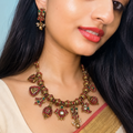 Woman wearing a traditional necklace and earrings with a plain background