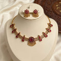 Gold necklace with red gemstones on a white stand